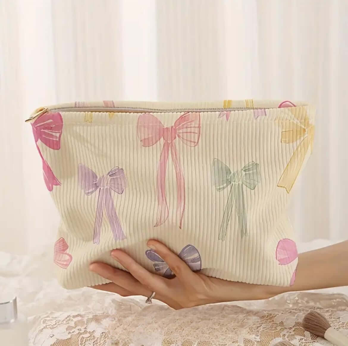 Lightweight Corduroy Toiletries & Accessories Makeup Bag with colorful bow print held by a hand.